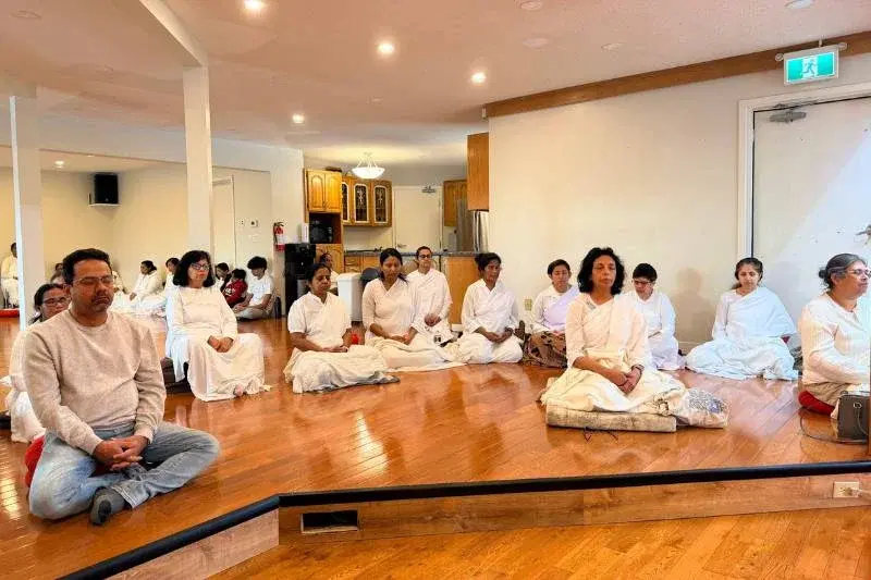 Participants in white clothing practicing present moment awareness meditation at Mahamevnawa Buddha Meditation Centre Winnipeg